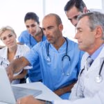 Doctor,Showing,Laptop,Pc,To,His,Colleagues,In,Medical,Office