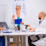 Portrait,Of,Mature,Woman,Doctor,Heading,Committee,Meeting,At,Medical