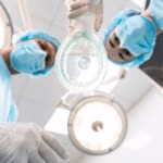 Two,Serious,Doctors,Wearing,Blue,Masks,And,Looking,At,You
