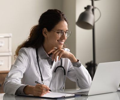 Smiling,Professional,Female,Doctor,Wearing,Glasses,And,Uniform,Taking,Notes