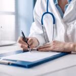 Doctor,Sitting,At,Desk,And,Writing,A,Prescription,For,Her
