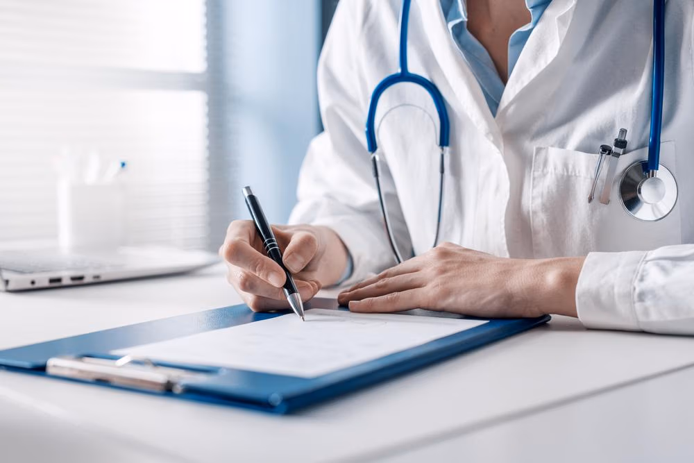 Doctor,Sitting,At,Desk,And,Writing,A,Prescription,For,Her