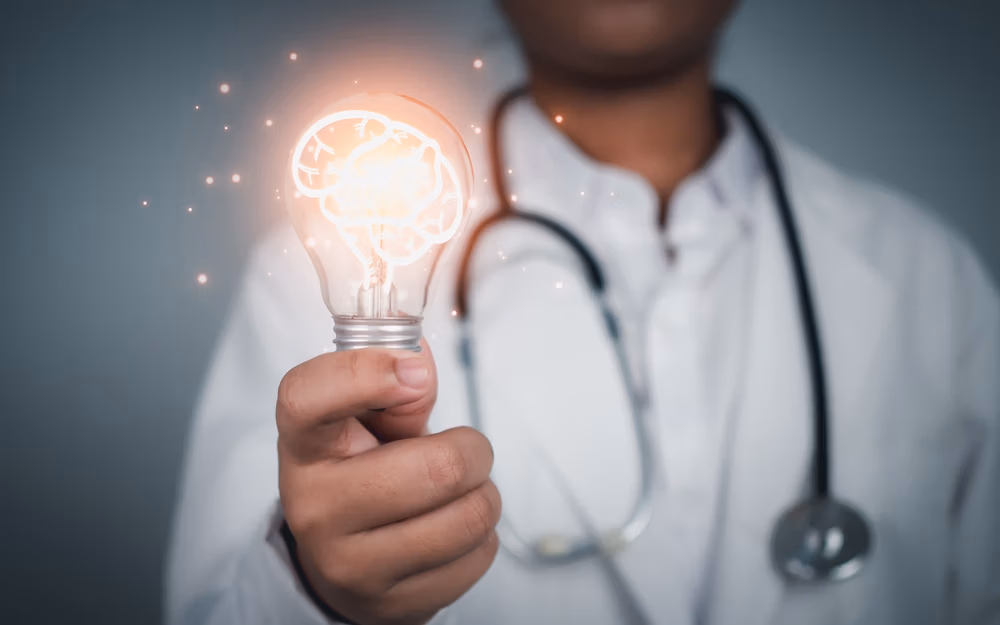 Doctor,Holding,Light,Bulb,With,Brain,Icon,Inside,On,Grey Doctor,Holding,Light,Bulb,With,Brain,Icon,Inside,On,Grey