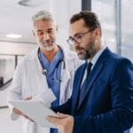Pharmaceutical,Sales,Representative,Talking,With,Doctor,In,Medical,Building,,Presenting