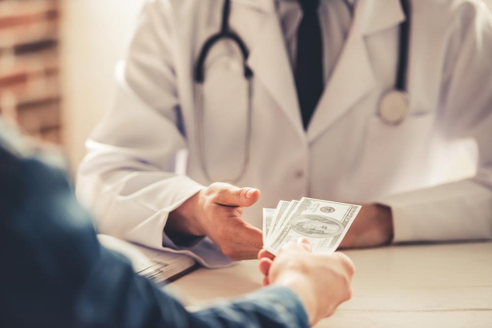 Cropped,Image,Of,Young,Doctor,In,White,Coat,Talking,Money