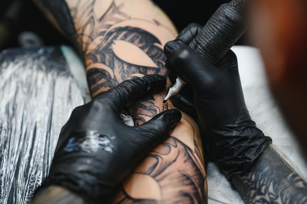 Cropped,Close,Up,Of,A,Bearded,Tattoo,Artist,Working,At